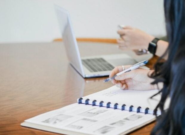 A woman holding a pen and thinking about automation tools every business should have