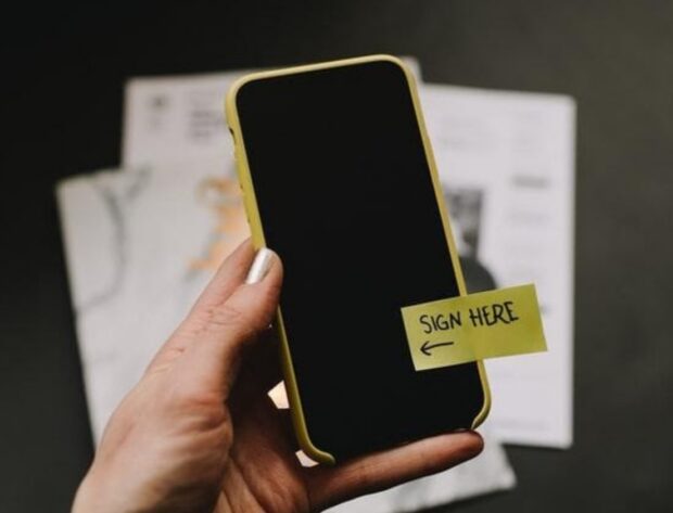 A phone with a sign here sticker on it.